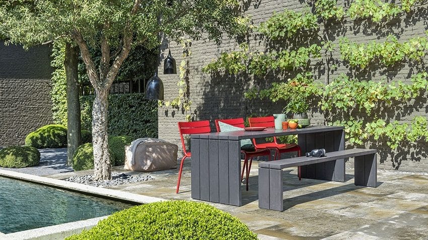 Terrassenplatte Mystika neben einen Pool eine Gartenbank und Tisch